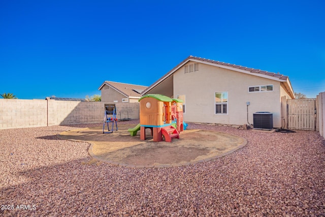 back of house with central AC and a playground