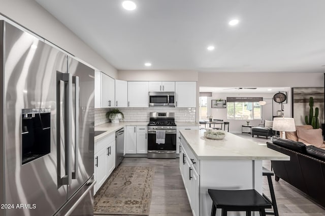 kitchen with a breakfast bar, white cabinets, dark hardwood / wood-style floors, ceiling fan, and appliances with stainless steel finishes