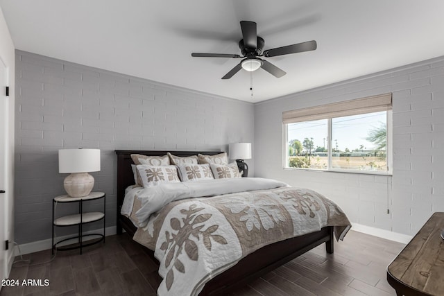 bedroom featuring ceiling fan, dark hardwood / wood-style flooring, and brick wall