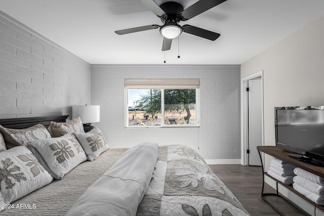 bedroom with dark hardwood / wood-style floors, ceiling fan, and brick wall