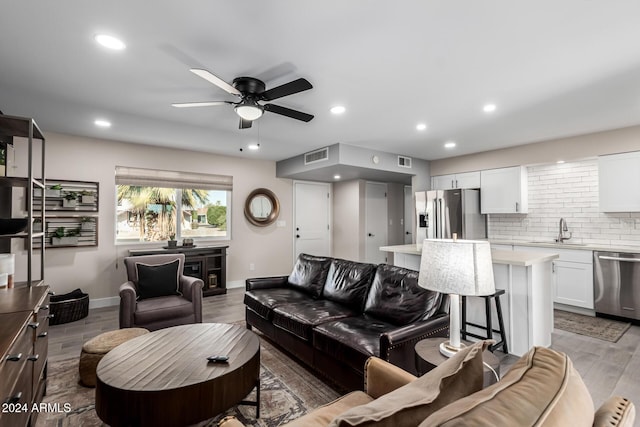 living room featuring ceiling fan, sink, and light wood-type flooring