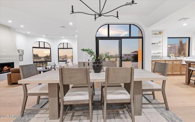 dining space featuring light wood-type flooring, a fireplace, visible vents, and recessed lighting