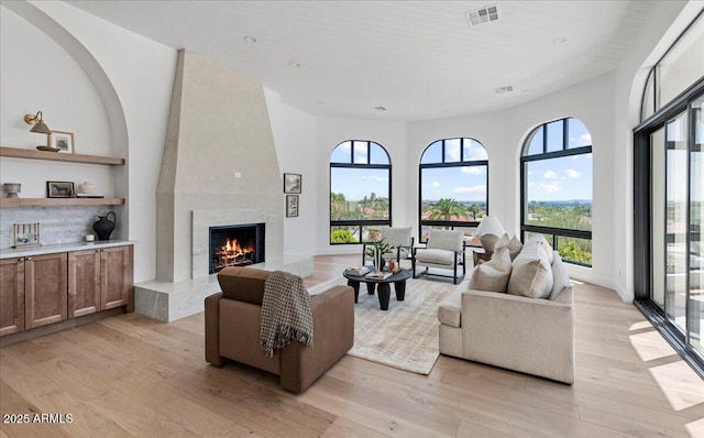 living room with visible vents, light wood-style floors, and a fireplace