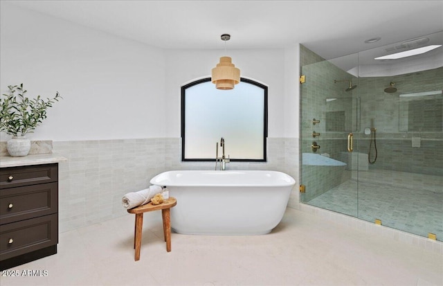 bathroom featuring a shower stall, a freestanding bath, tile walls, and wainscoting