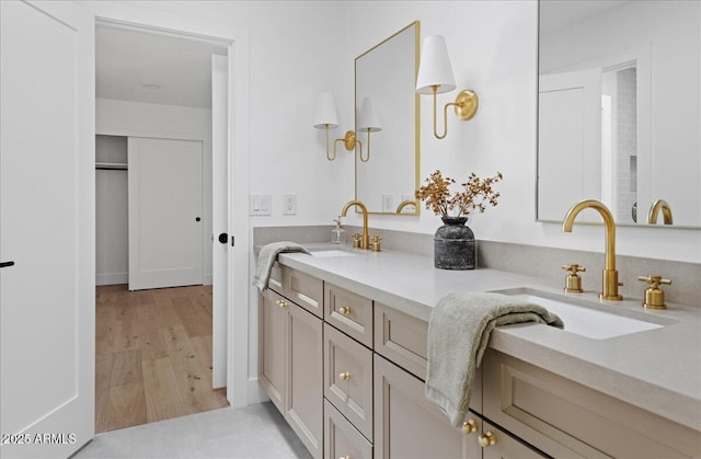 full bath featuring double vanity, a sink, and wood finished floors