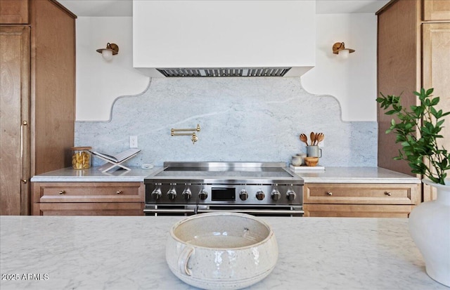 kitchen featuring custom range hood, high end stainless steel range, and brown cabinetry