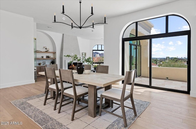 dining room featuring light wood finished floors, a notable chandelier, and baseboards