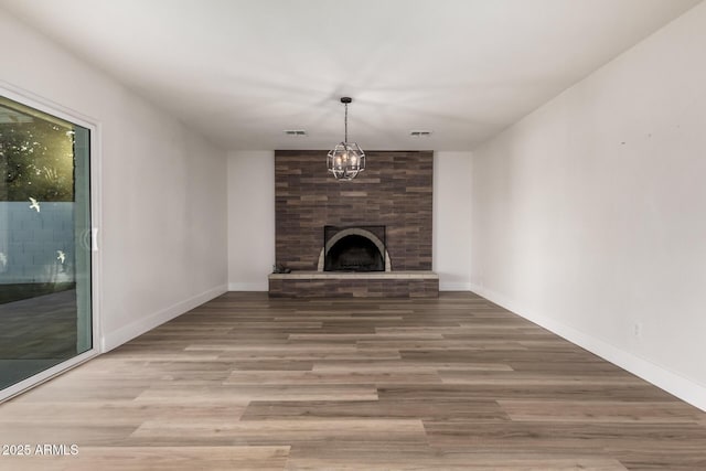 unfurnished living room with visible vents, a fireplace, baseboards, and wood finished floors