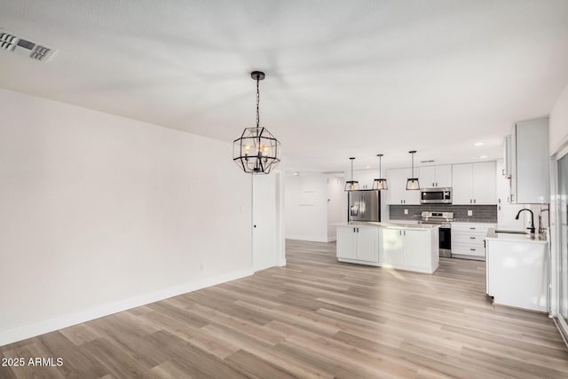 kitchen with visible vents, a center island, decorative backsplash, appliances with stainless steel finishes, and a sink