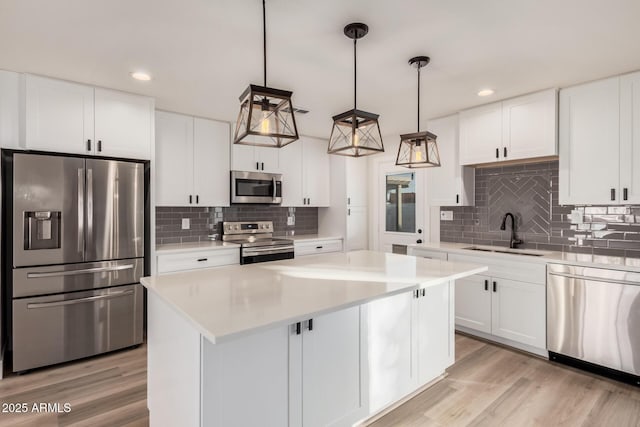 kitchen featuring light wood-style flooring, appliances with stainless steel finishes, light countertops, and a sink