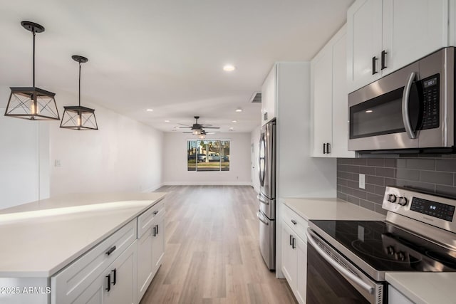 kitchen featuring light wood-type flooring, light countertops, appliances with stainless steel finishes, white cabinetry, and tasteful backsplash