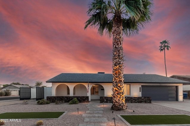 view of front of property with concrete driveway, covered porch, stucco siding, a garage, and a gate