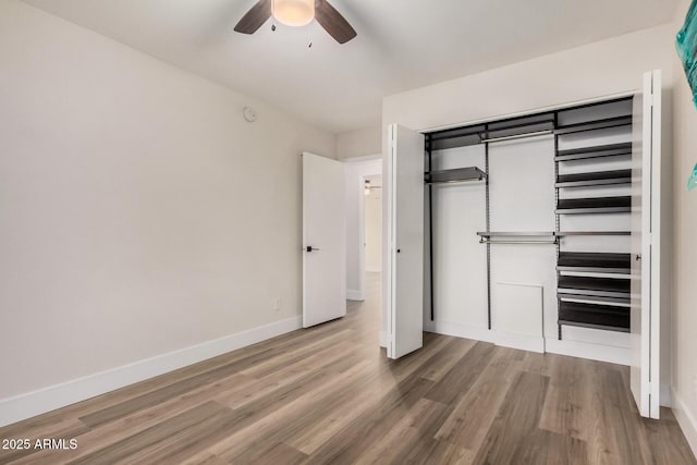 unfurnished bedroom with a closet, a ceiling fan, baseboards, and wood finished floors