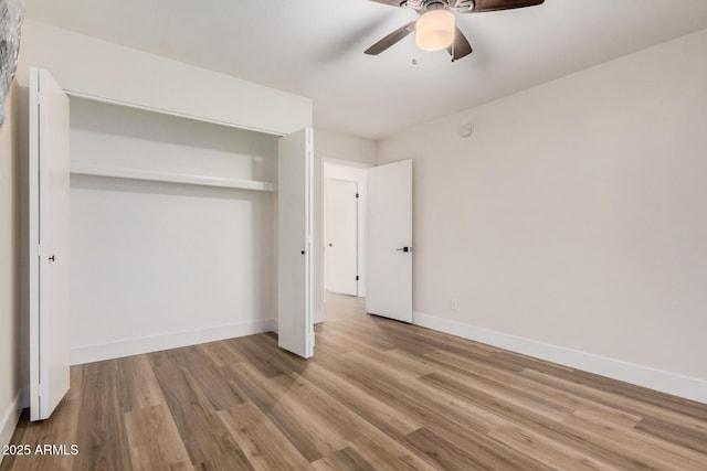 unfurnished bedroom featuring a closet, baseboards, wood finished floors, and a ceiling fan