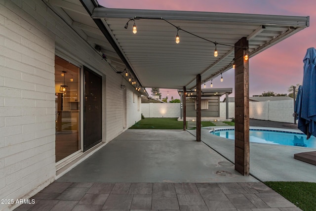 patio terrace at dusk with a fenced in pool and a fenced backyard