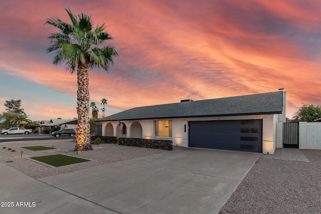 view of front of home featuring stucco siding, a gate, fence, concrete driveway, and a garage