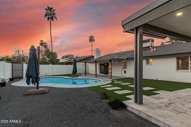 pool at dusk featuring a fenced backyard, a fenced in pool, and a patio