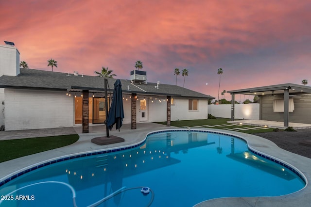 pool at dusk with a fenced in pool, a patio, and fence