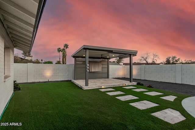 yard at dusk featuring an outdoor structure and a fenced backyard