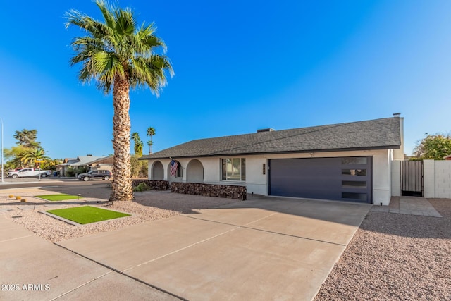 ranch-style house featuring stucco siding, driveway, a gate, fence, and a garage