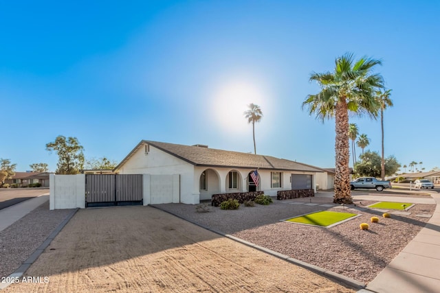 single story home featuring a garage, stucco siding, driveway, and a gate