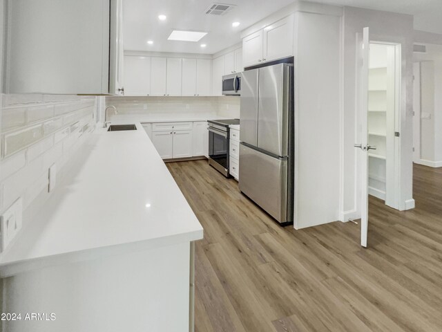 kitchen featuring white cabinets, appliances with stainless steel finishes, light wood-type flooring, and sink