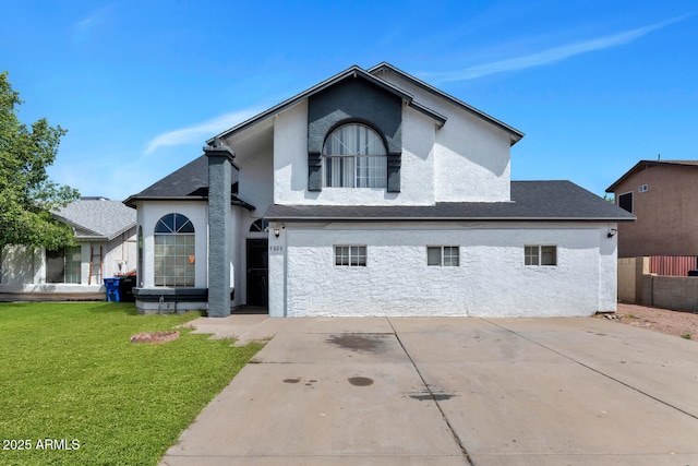 view of front of home with fence, driveway, a front yard, and stucco siding