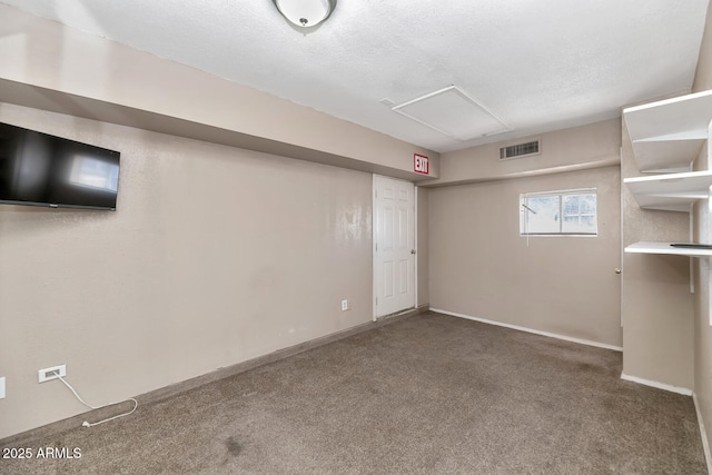 below grade area with visible vents, carpet flooring, baseboards, and a textured ceiling