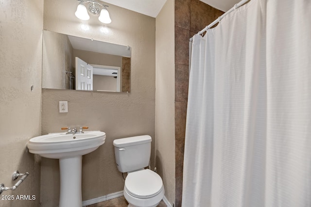 full bathroom with a textured wall, toilet, and a shower with shower curtain