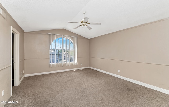 carpeted empty room featuring baseboards, ceiling fan, and vaulted ceiling