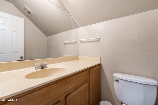 half bath with toilet, vaulted ceiling, visible vents, and vanity