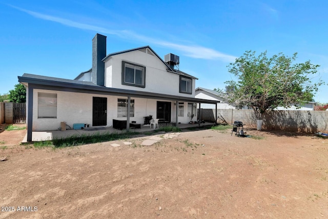 rear view of house with a fenced backyard, a chimney, central AC, and a patio area
