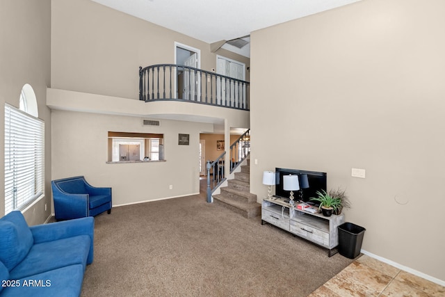 living room featuring baseboards, a high ceiling, a healthy amount of sunlight, and stairway