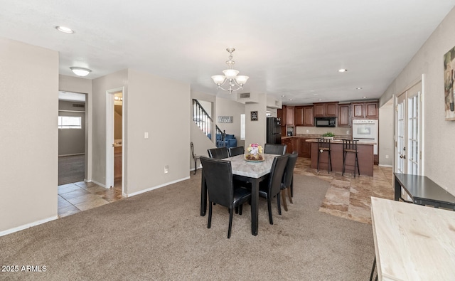 dining room featuring visible vents, an inviting chandelier, stairs, baseboards, and light colored carpet