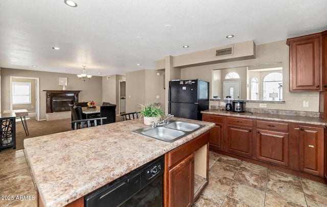 kitchen with visible vents, a center island with sink, light countertops, a sink, and black appliances