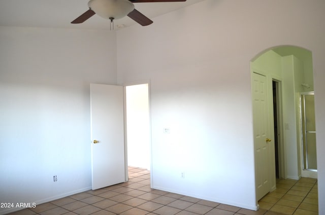 tiled spare room featuring a high ceiling and ceiling fan