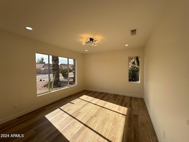 unfurnished room with baseboards, visible vents, dark wood finished floors, and recessed lighting