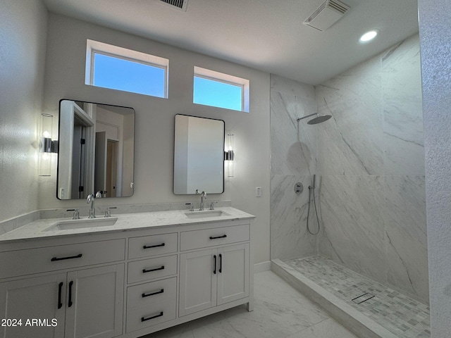 bathroom with marble finish floor, a marble finish shower, a sink, and visible vents