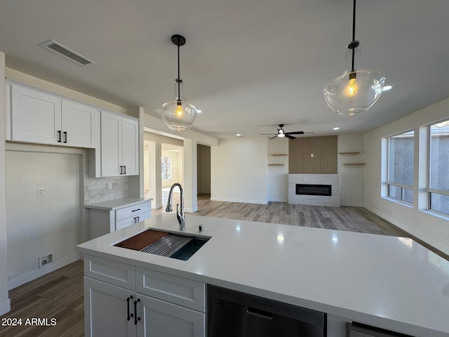 kitchen with black dishwasher, open floor plan, decorative light fixtures, light countertops, and a sink