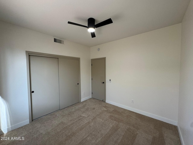 unfurnished bedroom featuring light carpet, baseboards, visible vents, a ceiling fan, and a closet