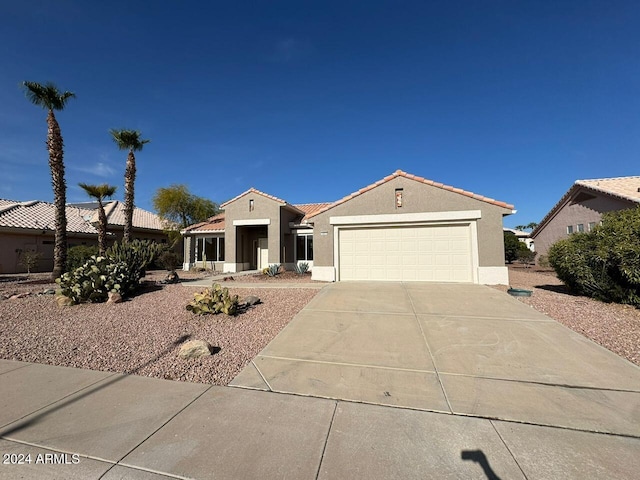 mediterranean / spanish-style house with a garage, concrete driveway, a tile roof, and stucco siding