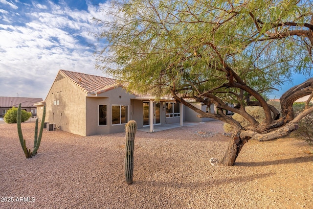 back of property with central AC, a patio, a tiled roof, and stucco siding