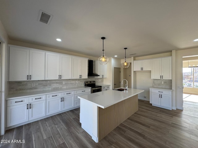 kitchen featuring light countertops, visible vents, white cabinets, stainless steel range with electric cooktop, and an island with sink