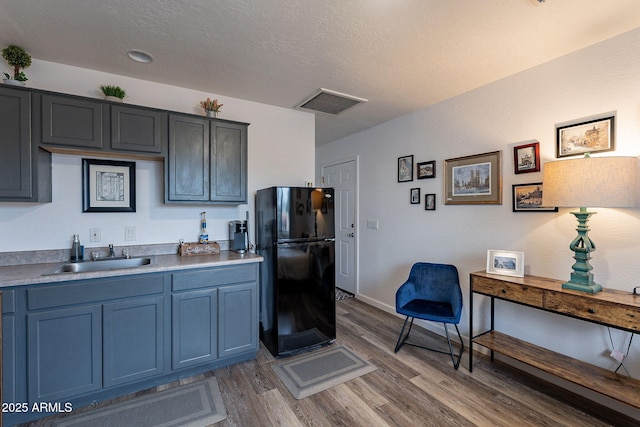 2731 E Windsor Ave, Phoenix, AZ 85008 - kitchen featuring freestanding refrigerator, a sink, wood finished floors, light countertops, and blue cabinetry