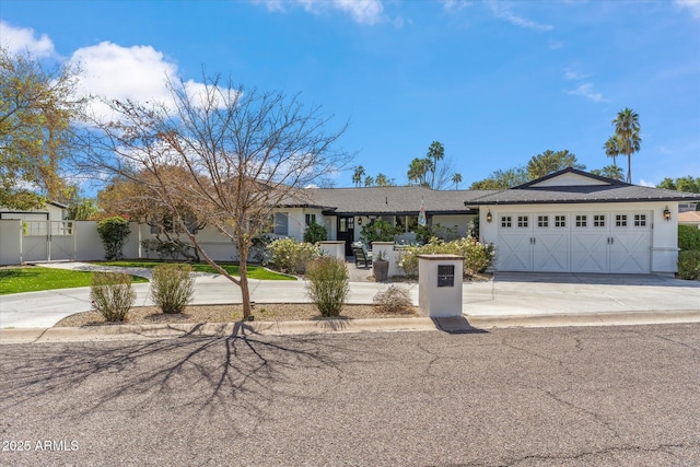 ranch-style home featuring driveway, fence, an attached garage, and stucco siding