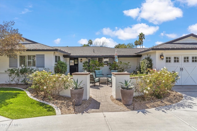 ranch-style house with a garage, driveway, outdoor lounge area, and stucco siding