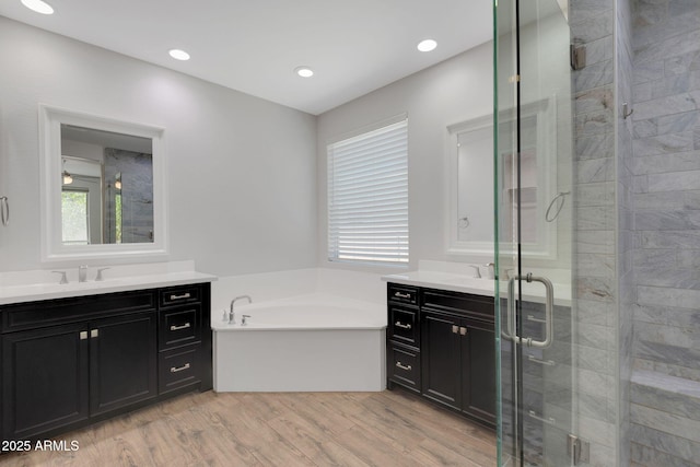 4853 N 183rd Ln, Goodyear, AZ 85395 - bathroom with two vanities, a shower stall, a garden tub, wood finished floors, and recessed lighting