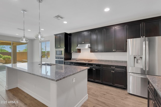 4853 N 183rd Ln, Goodyear, AZ 85395 - kitchen with appliances with stainless steel finishes, a sink, under cabinet range hood, light stone countertops, and a kitchen island with sink