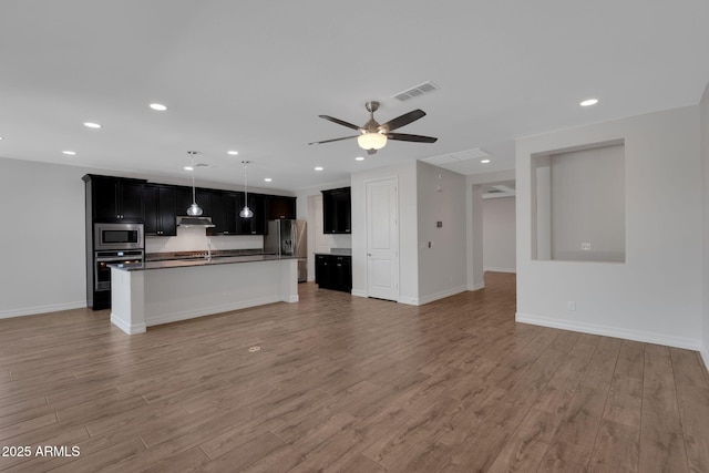 4853 N 183rd Ln, Goodyear, AZ 85395 - kitchen featuring stainless steel appliances, open floor plan, dark countertops, recessed lighting, and light wood-type flooring