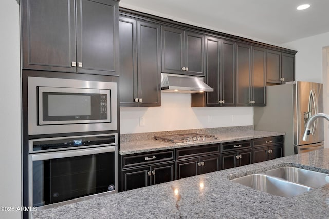 4853 N 183rd Ln, Goodyear, AZ 85395 - kitchen with appliances with stainless steel finishes, under cabinet range hood, light stone counters, a sink, and recessed lighting